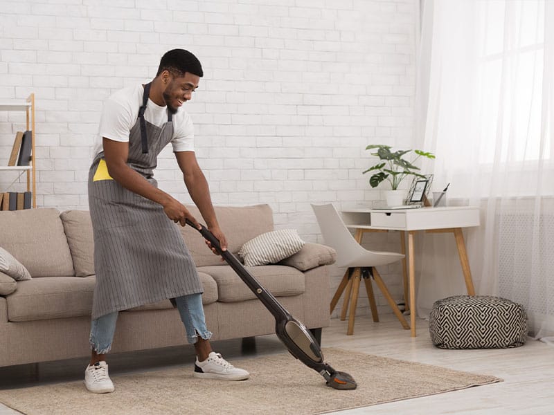 African American man cleaning house with a wireless vacuum